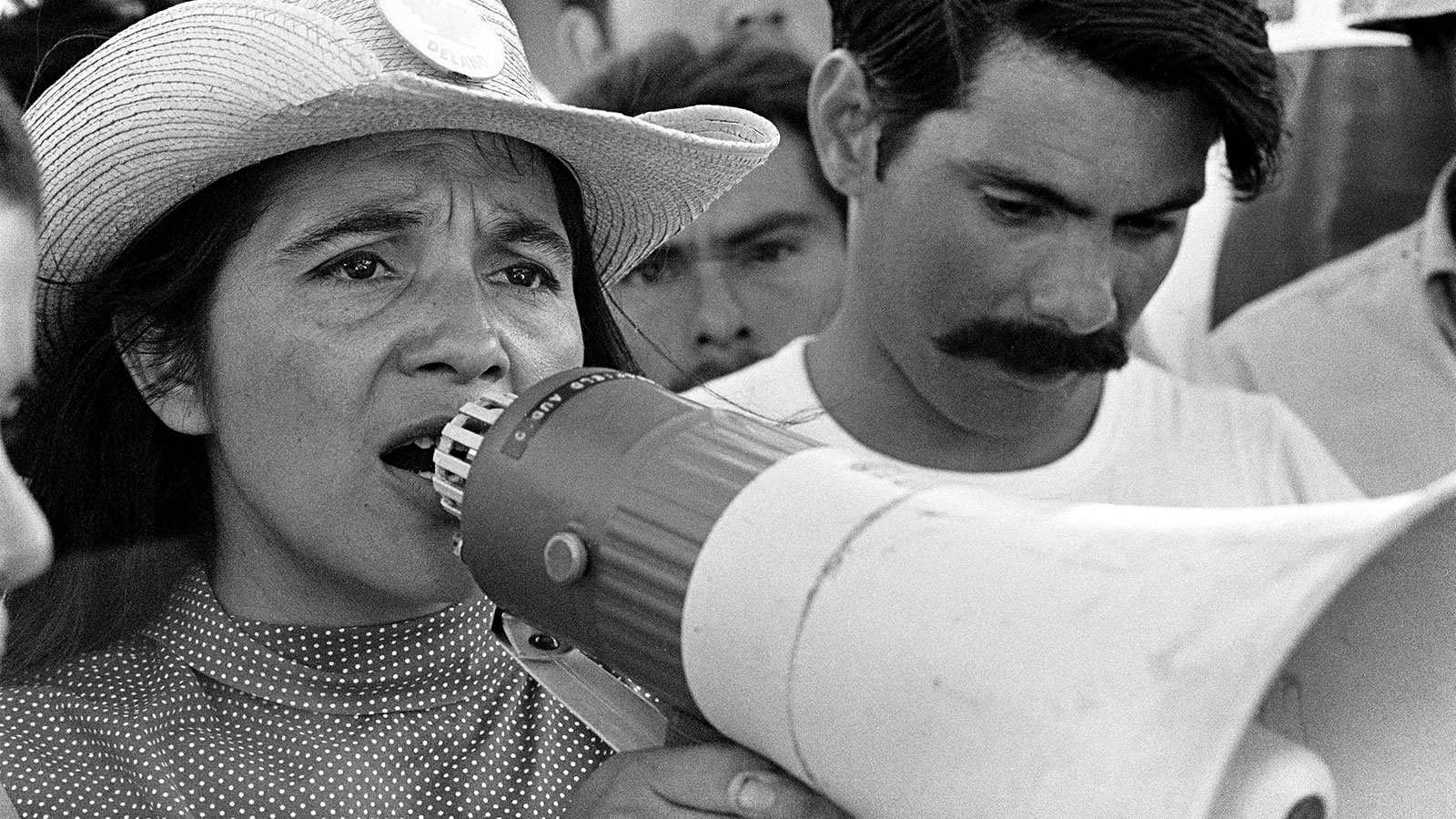 Black and white image of Dolores Huerta speaking into a megaphone.