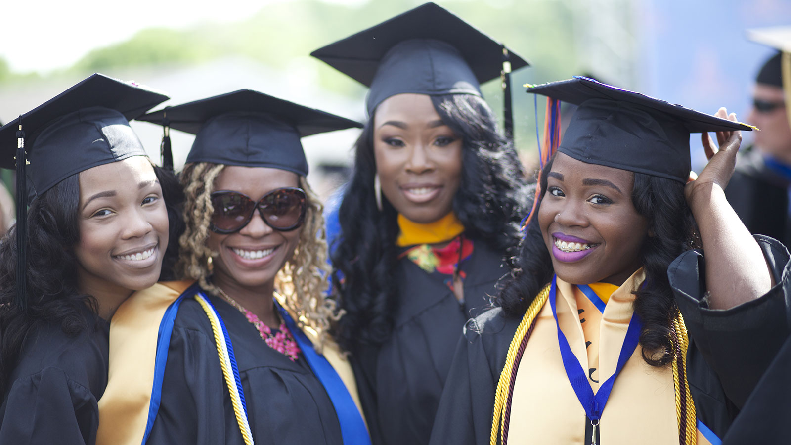 4 African American smiling and women wearing cap and gown